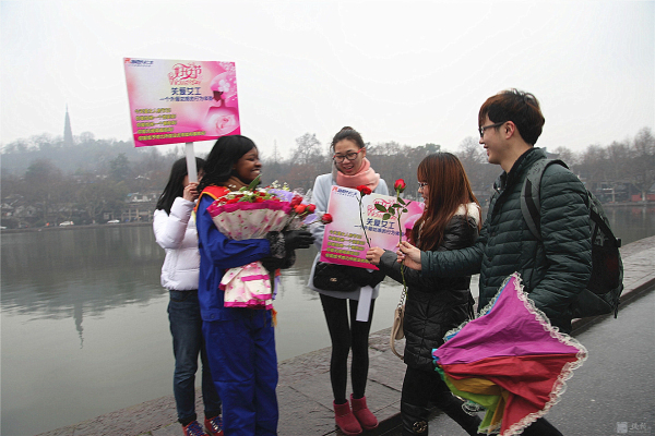 外籍女工西湖边“关爱女工”行为体验 游人的热情拥抱累得她胳膊抬不起来